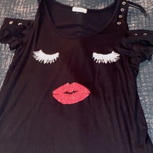 A black cold shoulder top with chic face print!